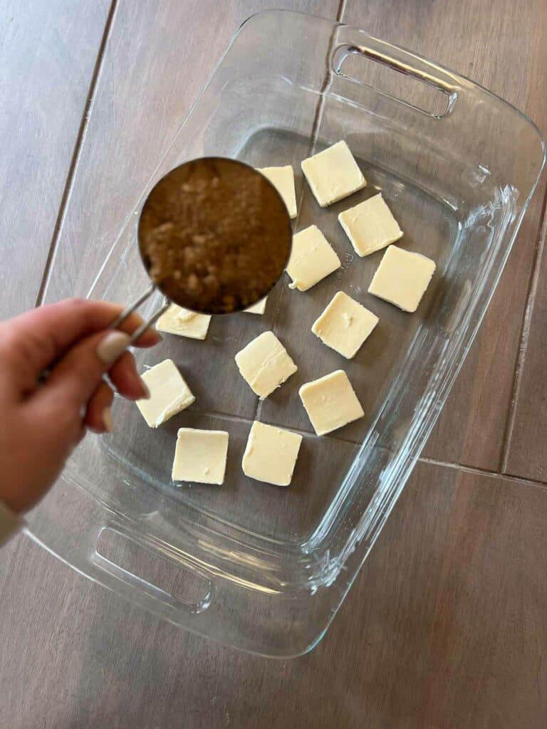 Gluten free pineapple upside down cake being made by butter and brown sugar going into pan