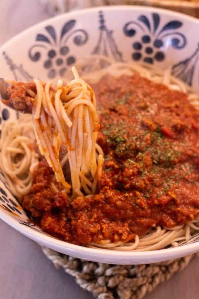 Gluten Free Spaghetti in a blue decorative bowl with pasta on a spoon