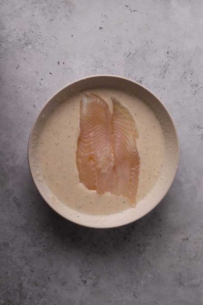 Restaurant Style Gluten Free Fish and Chips dry and wet ingredients in a bowl mixed with fish dredged in