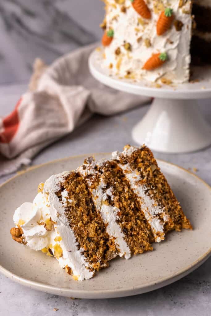 The BEST Gluten Free Carrot Cake on a cake stand with a piece cut out