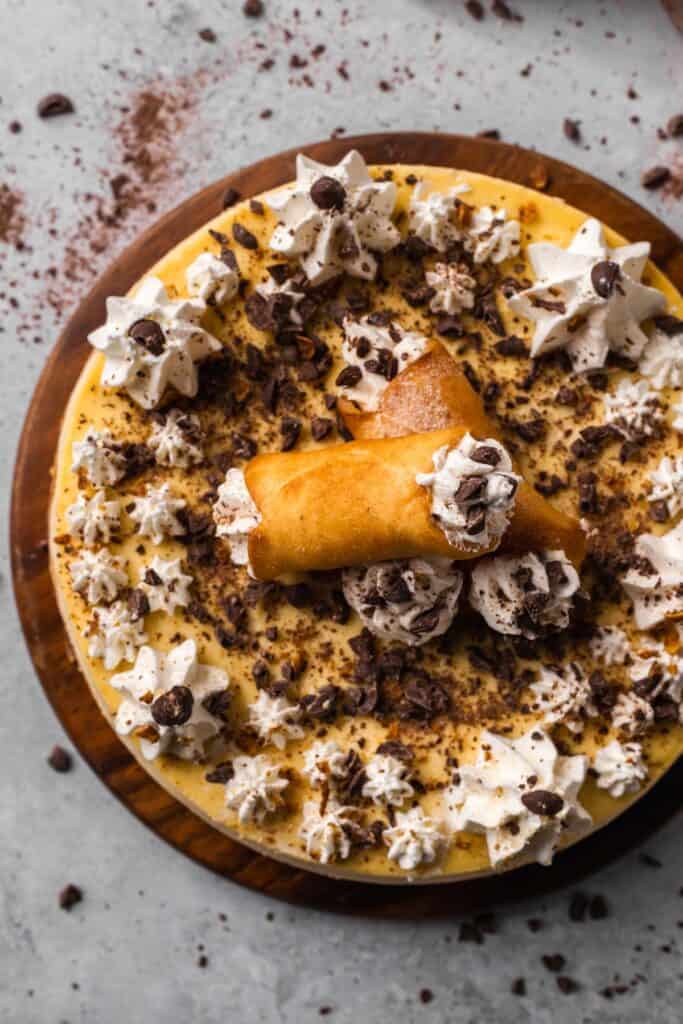 Cannoli Cheesecake with whipped cream and cannolis on top