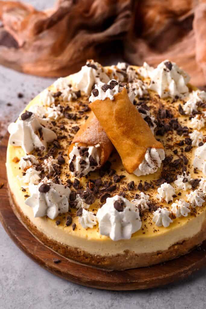 Cannoli Cheesecake with whipped cream and cannolis on top
