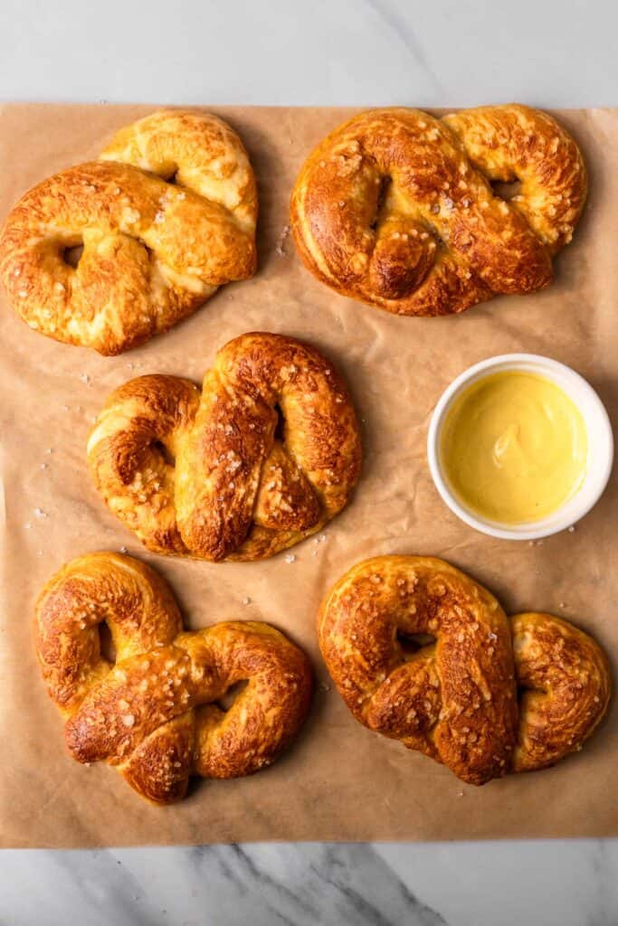 Gluten Free Soft Pretzels on parchment paper next to melted cheddar cheese