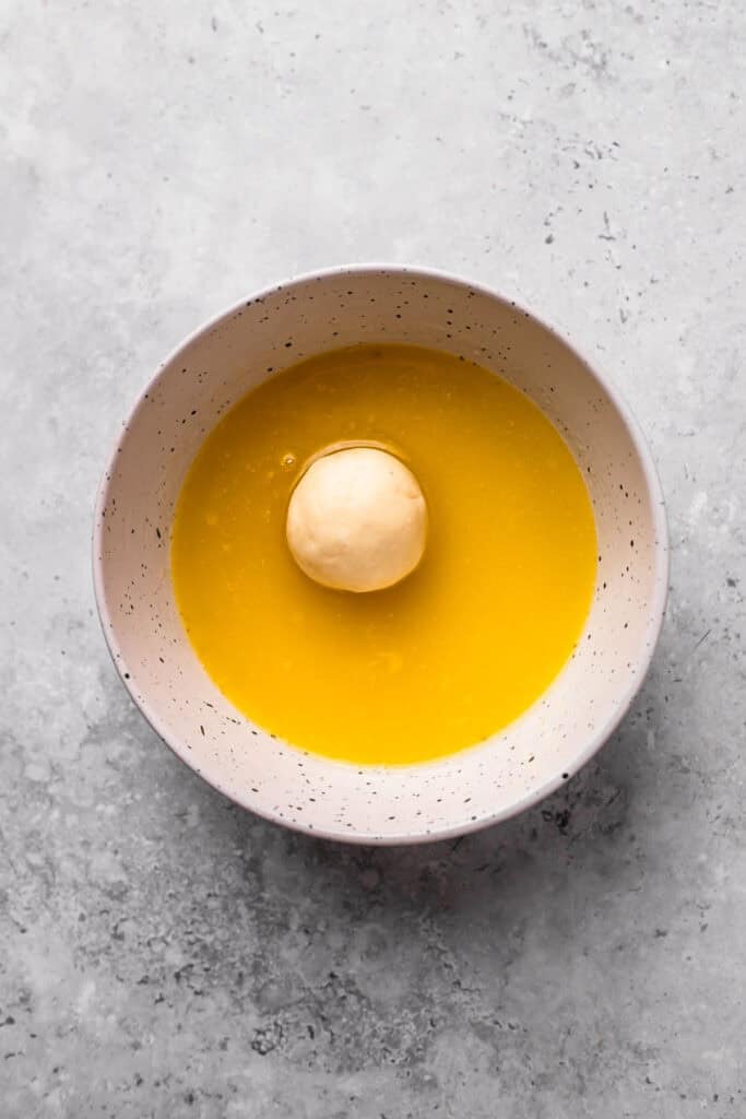 Soft Gluten Free Monkey Bread dough ball in butter in a bowl