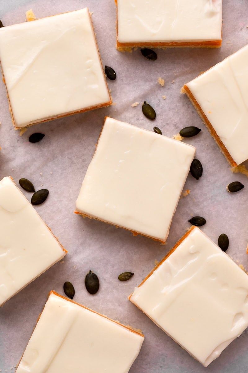 Multiple Layered Gluten Free Pumpkin Bars cut on with black pumpkin seeds, overhead view