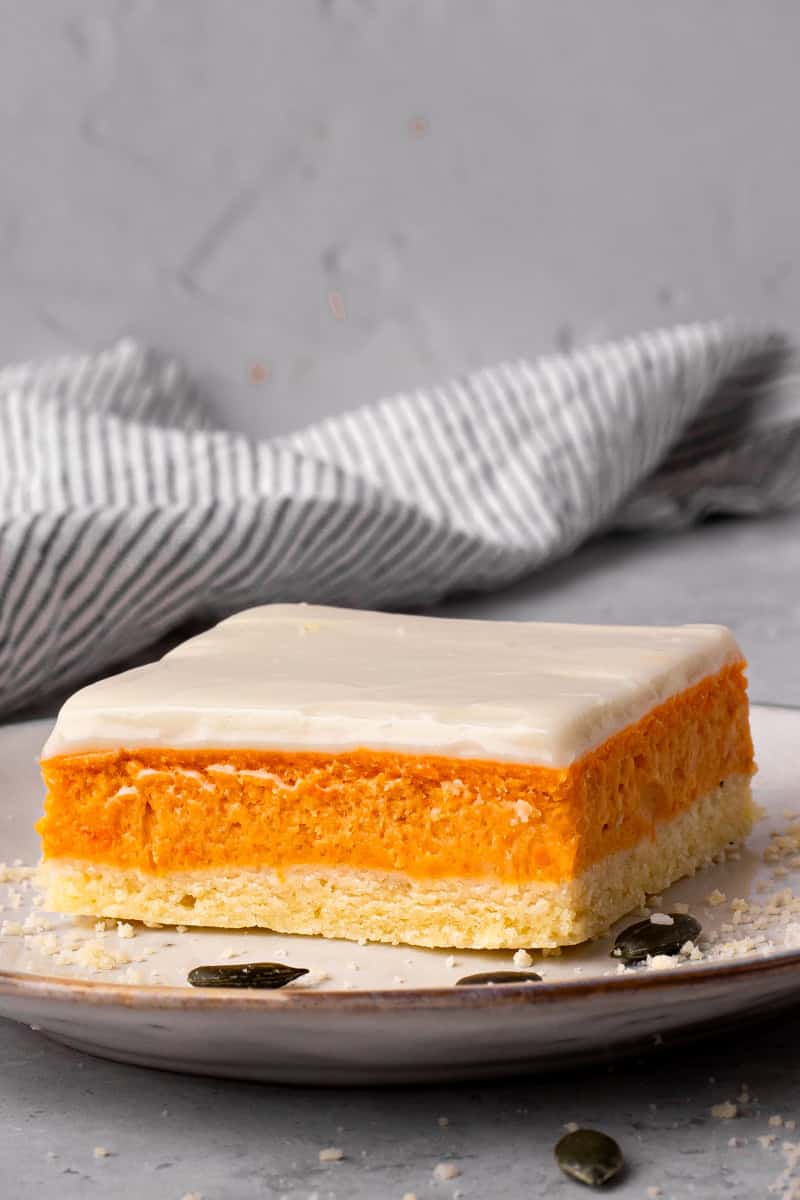 Layered Gluten Free Pumpkin Bars cut on a plate with black pumpkin seeds