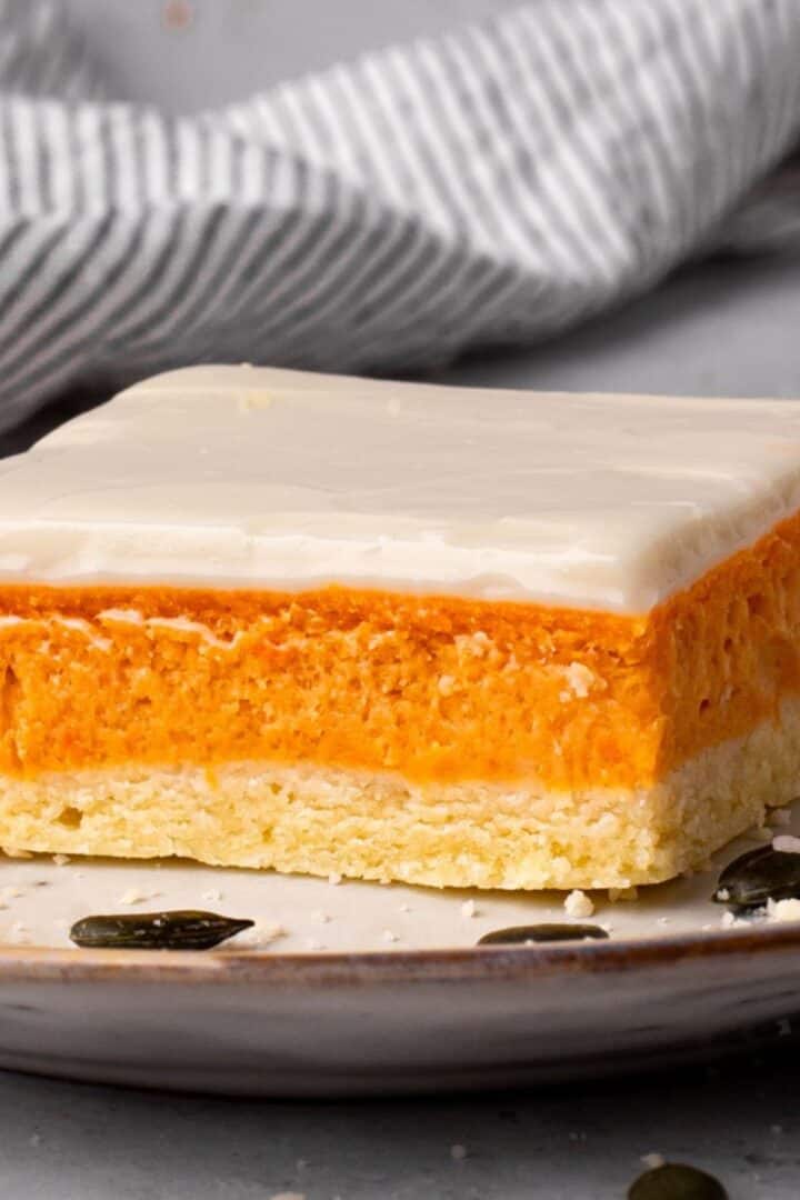 Multiple Layered Gluten Free Pumpkin Bars cut on a plate with black pumpkin seeds