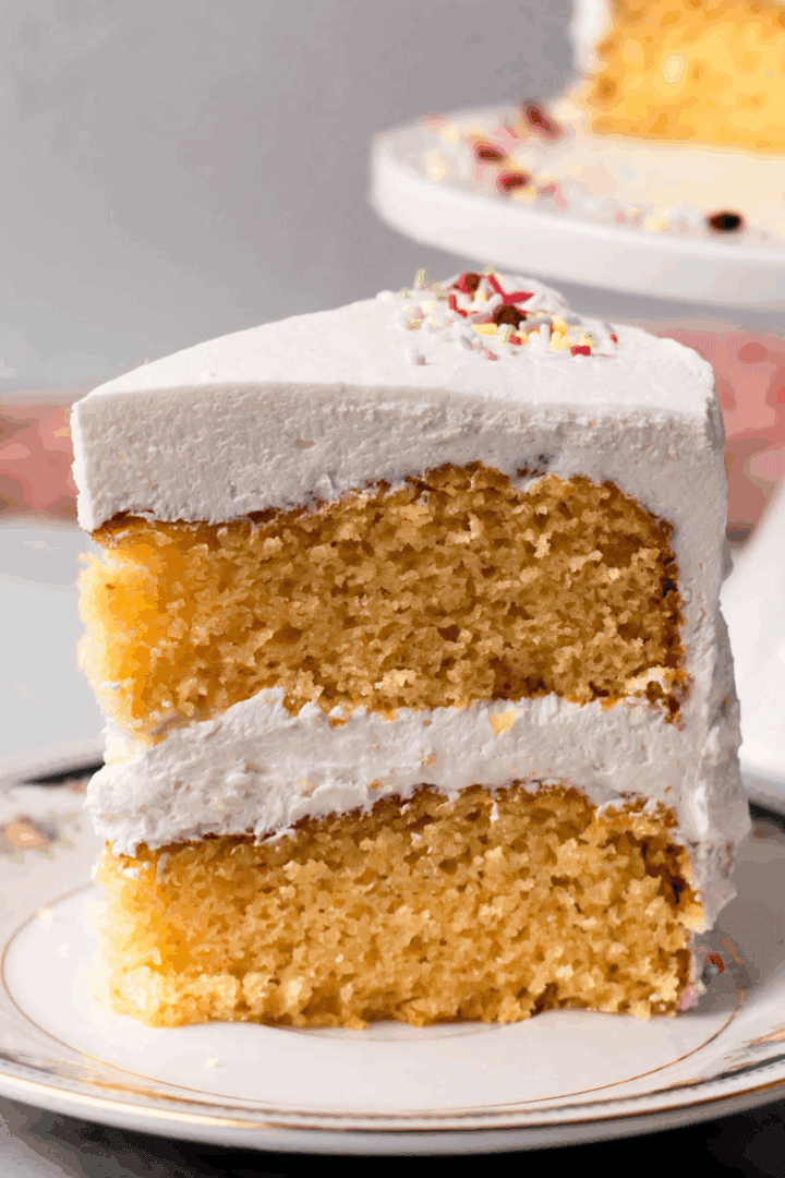 Slice of gluten free cake with vanilla buttercream frosting on a white plate