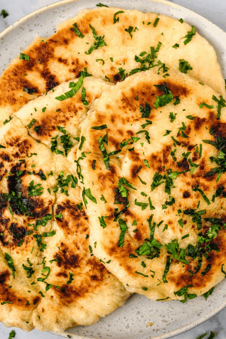 Gluten Free Naan Bread on a white plate topped with parsley and melted butter