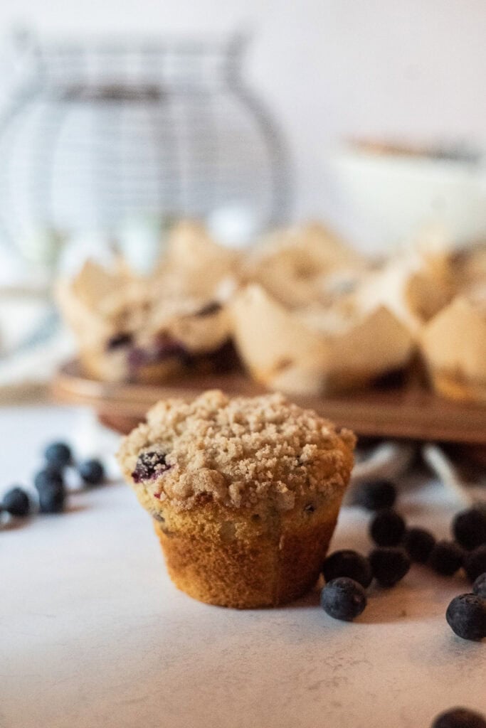 Gluten free blueberry muffins with crumble on top and blueberries near