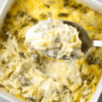 hot artichoke dip with a spoon fill scooped out with title above the image