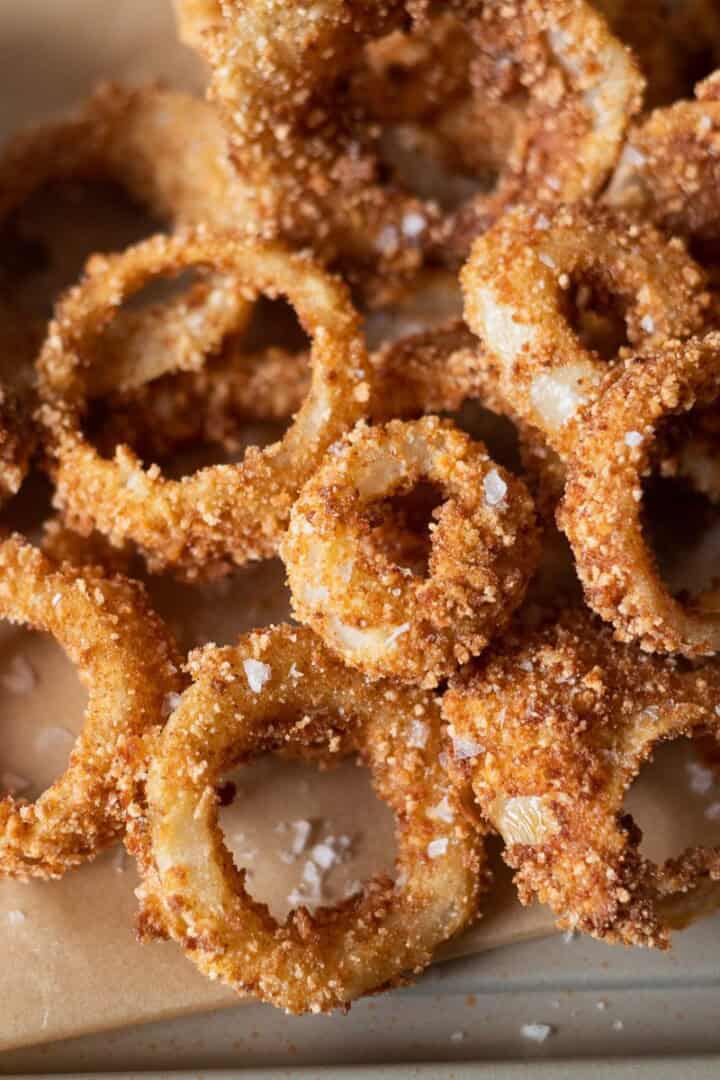 Extra Crispy Gluten Free Onion Rings (with a Secret Ingredient) on a baking sheet with ketchup and salt
