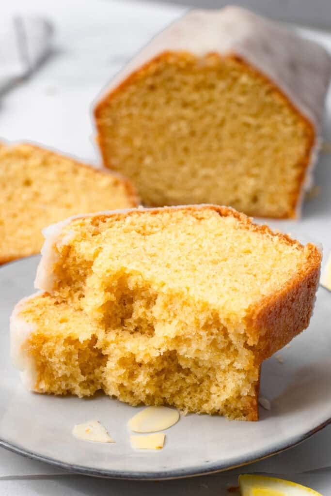 A slice of gluten free lemon pound cake with vanilla glaze on a plate