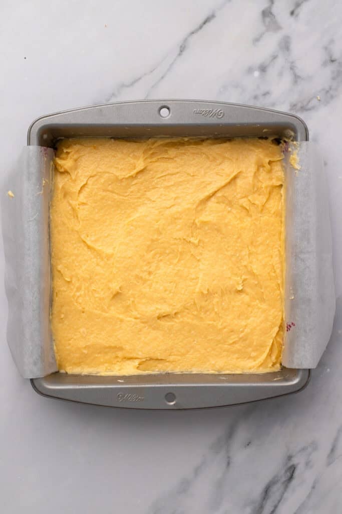 A pan filled with yellow batter on a marble counter