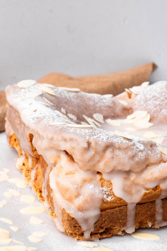 A piece of cake with icing and almonds on a plate
