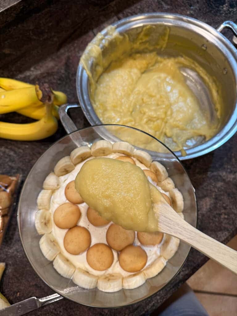 Pudding being spooned over cookie layer of banana pudding