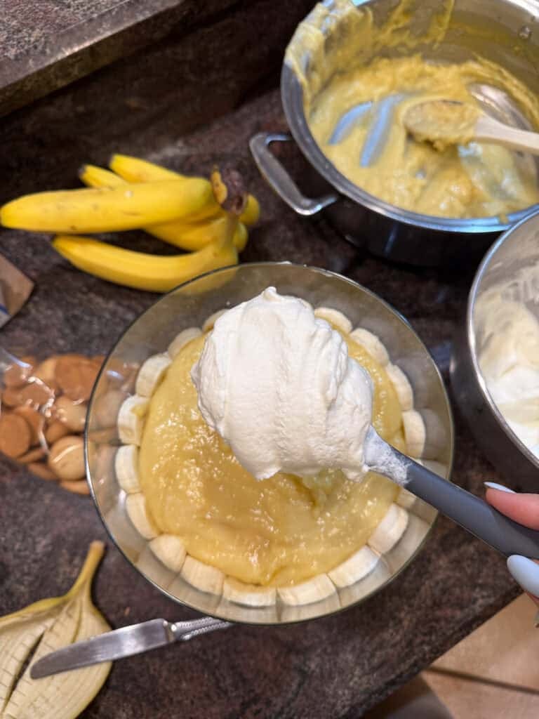 Whipped cream being layered on pudding layer