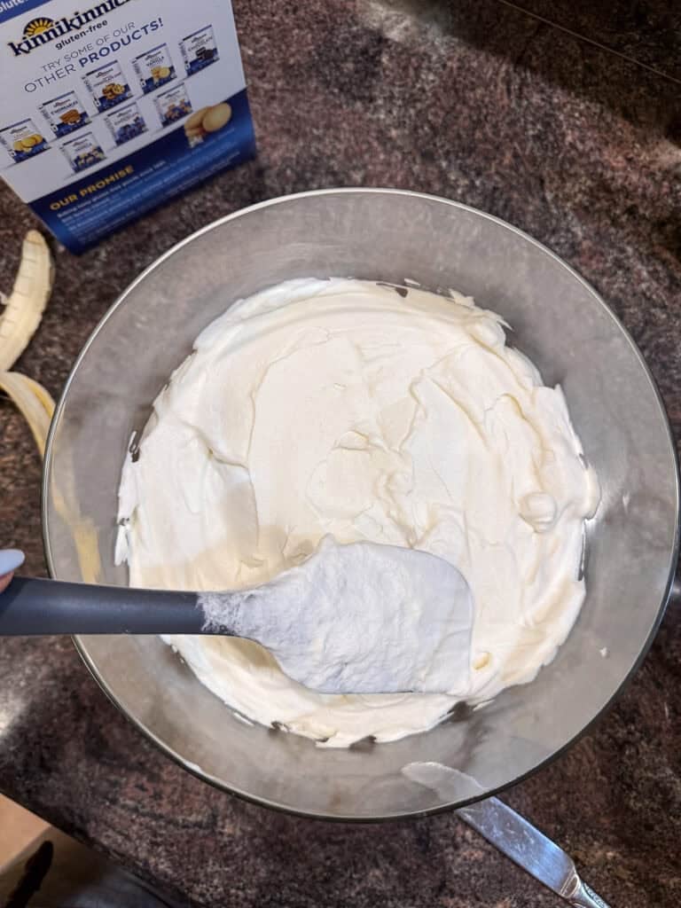 Whipped cream being spread in trifle dish