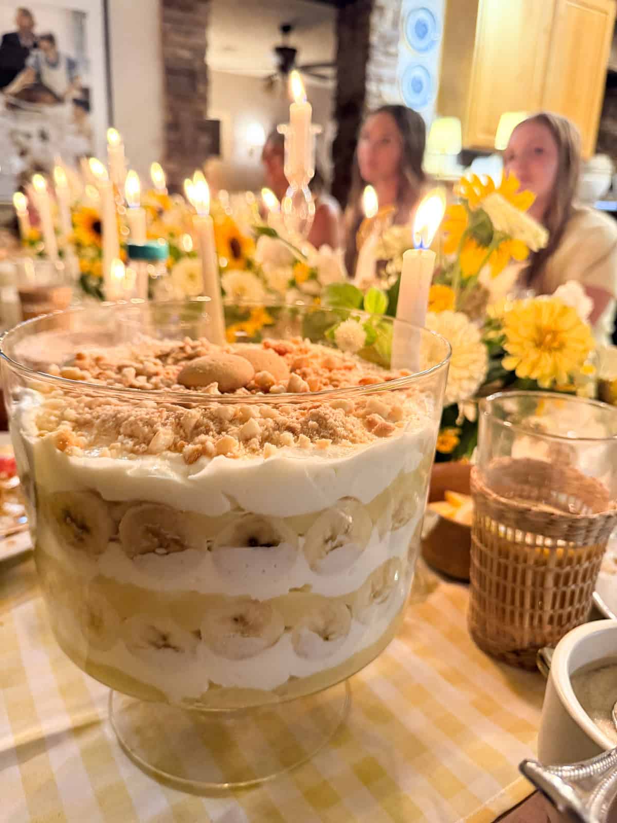 Gluten free banana pudding in a trifle dish with candles in the background