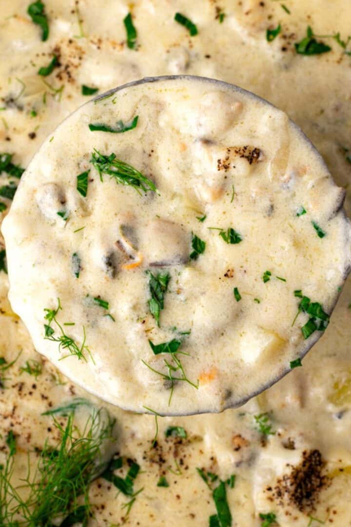 Creamy gluten free clam chowder in a pot with fresh herbs on top