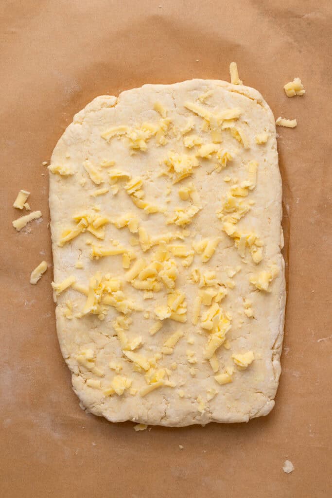 Gluten free cheddar biscuits dough rolled out with cheese grated on top
