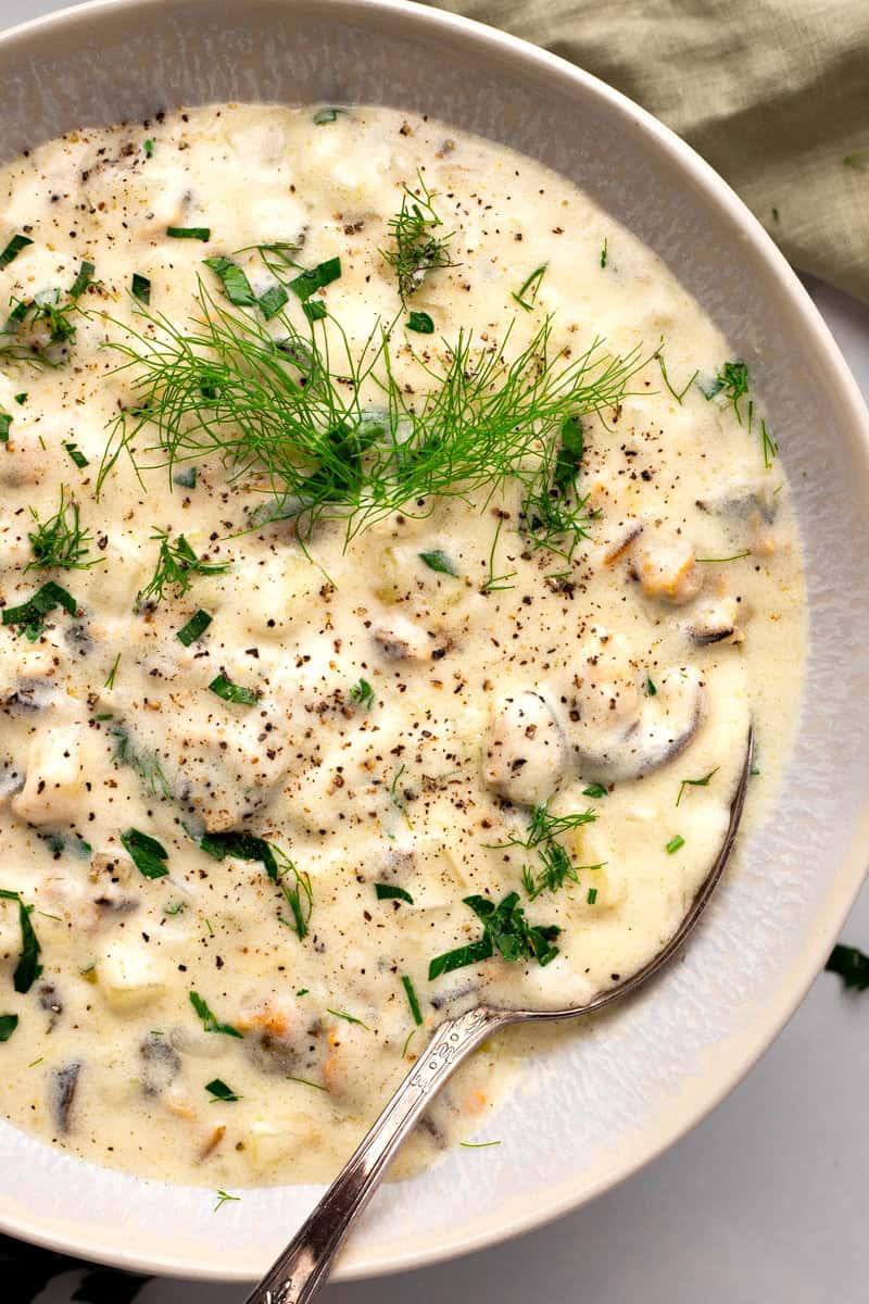 Creamy gluten free clam chowder in a pot with fresh herbs on top