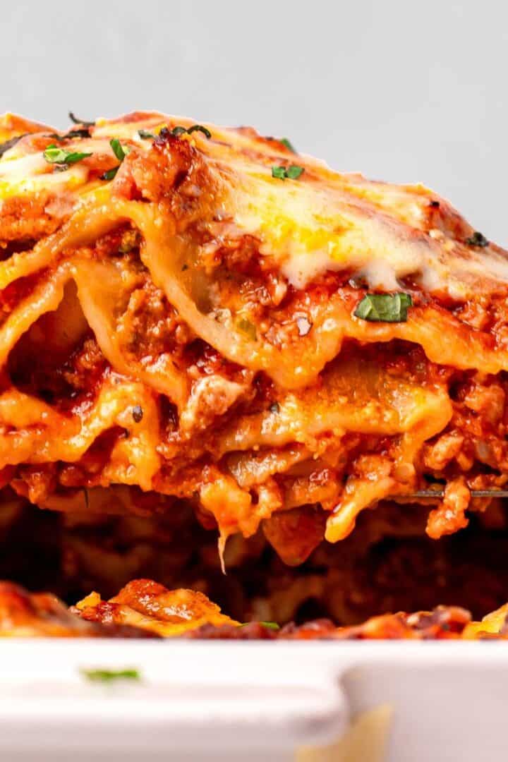 Homemade Gluten Free Lasagna piece on a spatula coming out of the pan