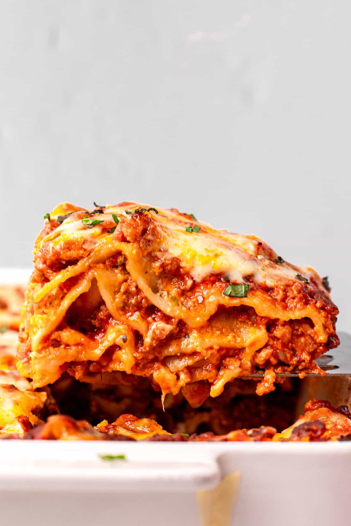 Homemade Gluten Free Lasagna piece on a spatula coming out of the pan