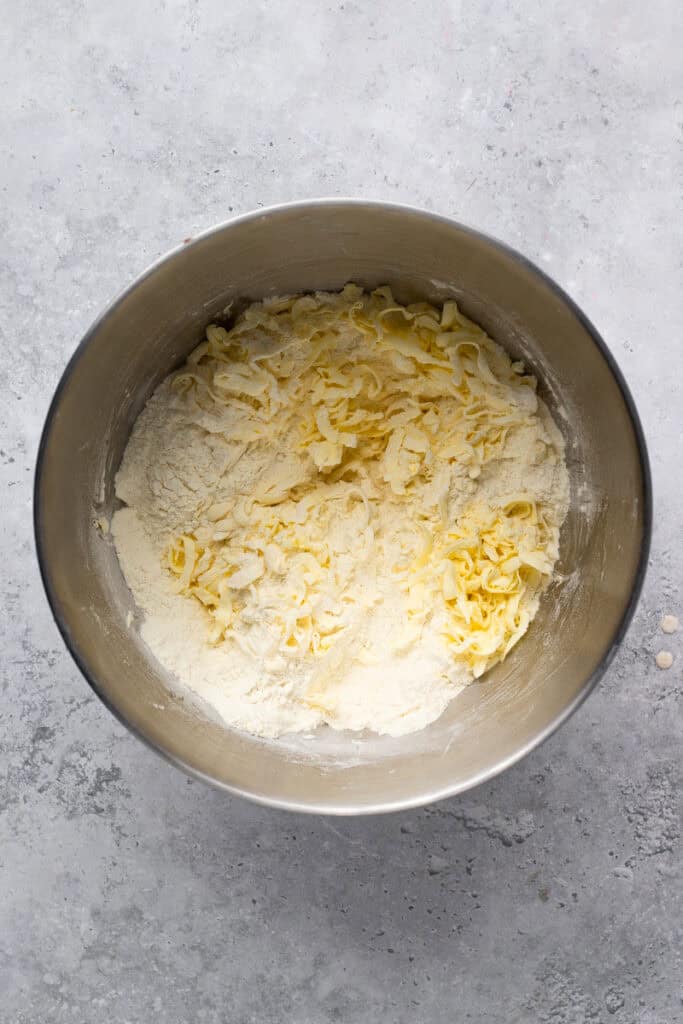 Homemade Gluten Free Apple Pie with Flaky Crust being made with butter grated