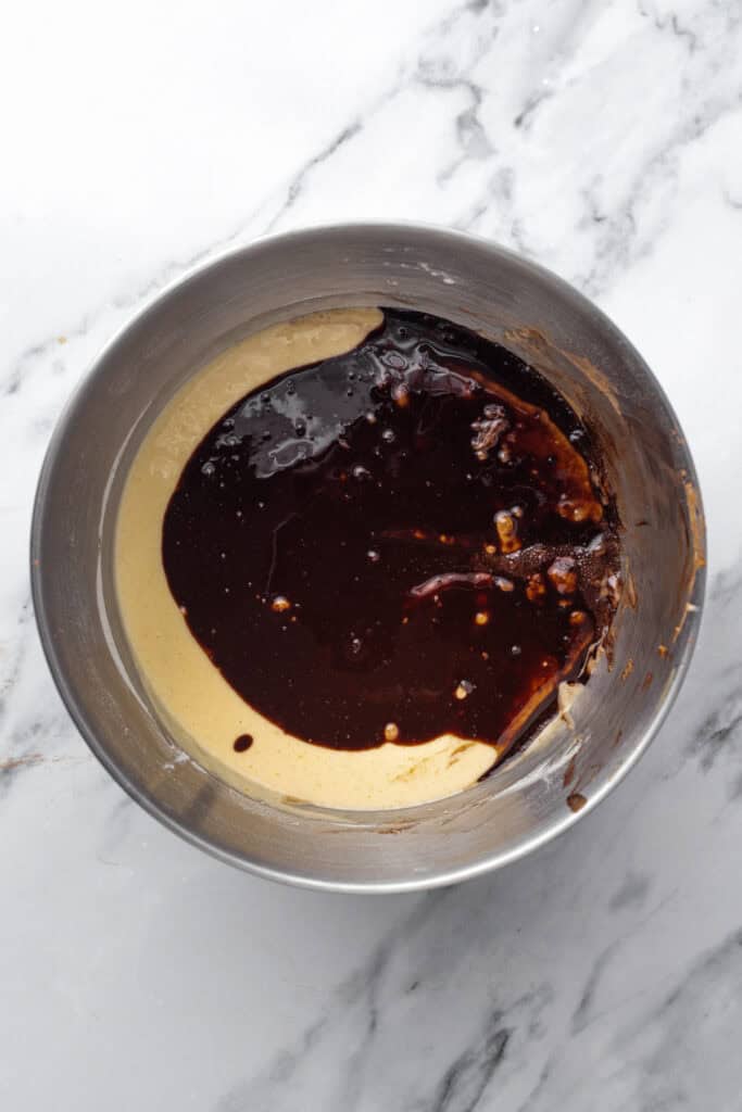 Chocolate cake batter in a silver bowl before it is mixed showing two different colors.