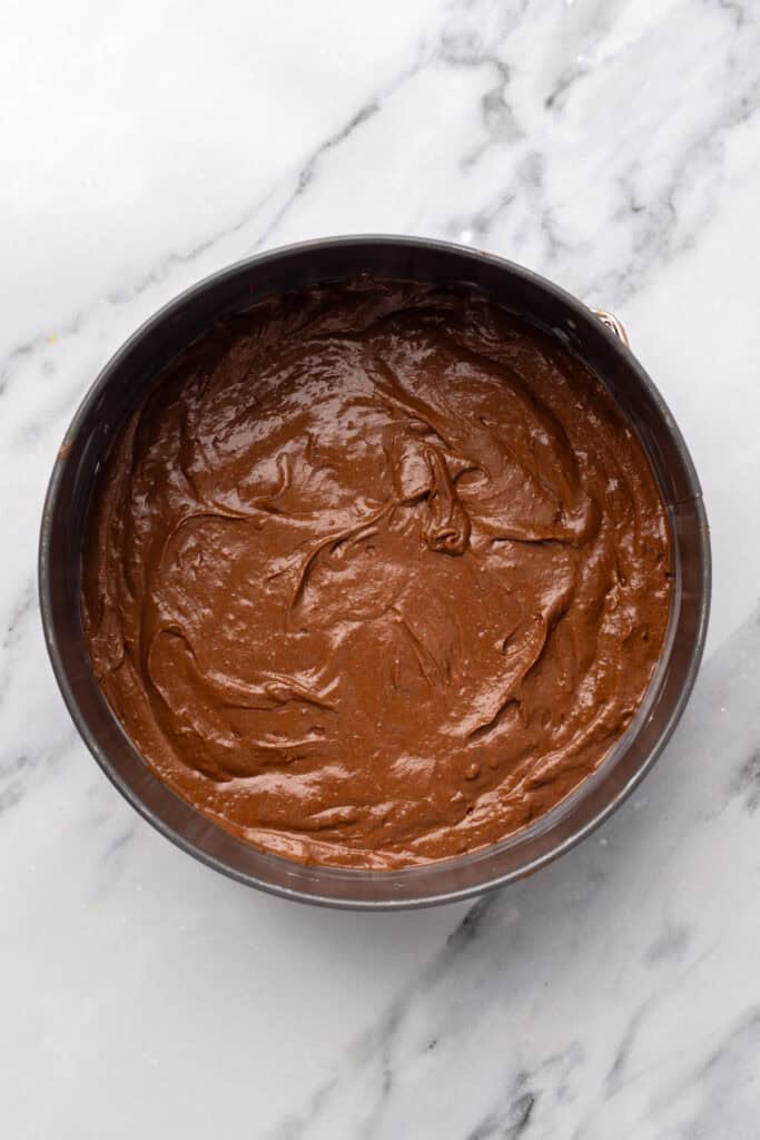 Chocolate cake batter in a silver bowl.