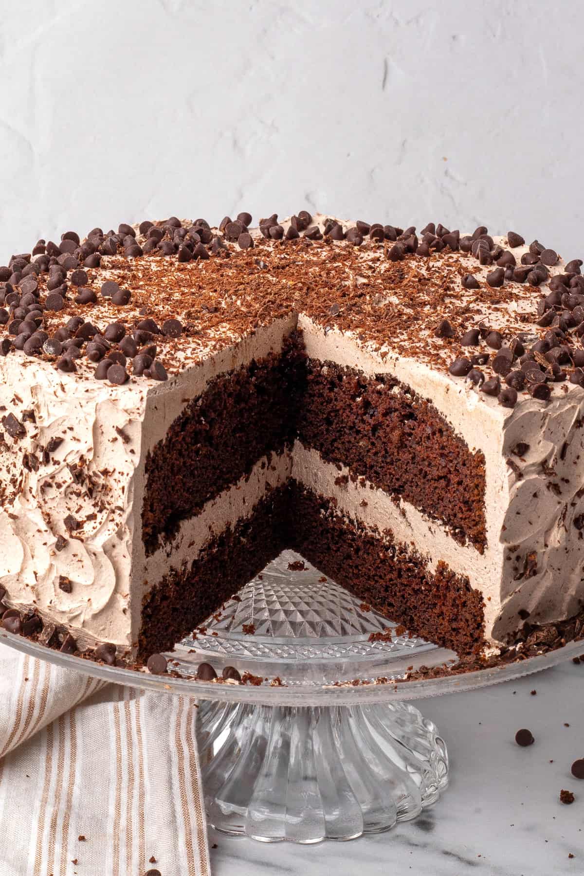 The BEST Gluten Free Chocolate Cake slice cut out, frosted with a slice removed showing the rest of the whole cake.