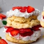 Stacked gluten free strawberry shortcakes with whipped cream and fresh sliced strawberries