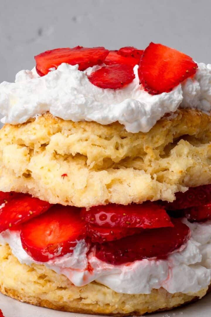 Stacked gluten free strawberry shortcakes with whipped cream and fresh sliced strawberries