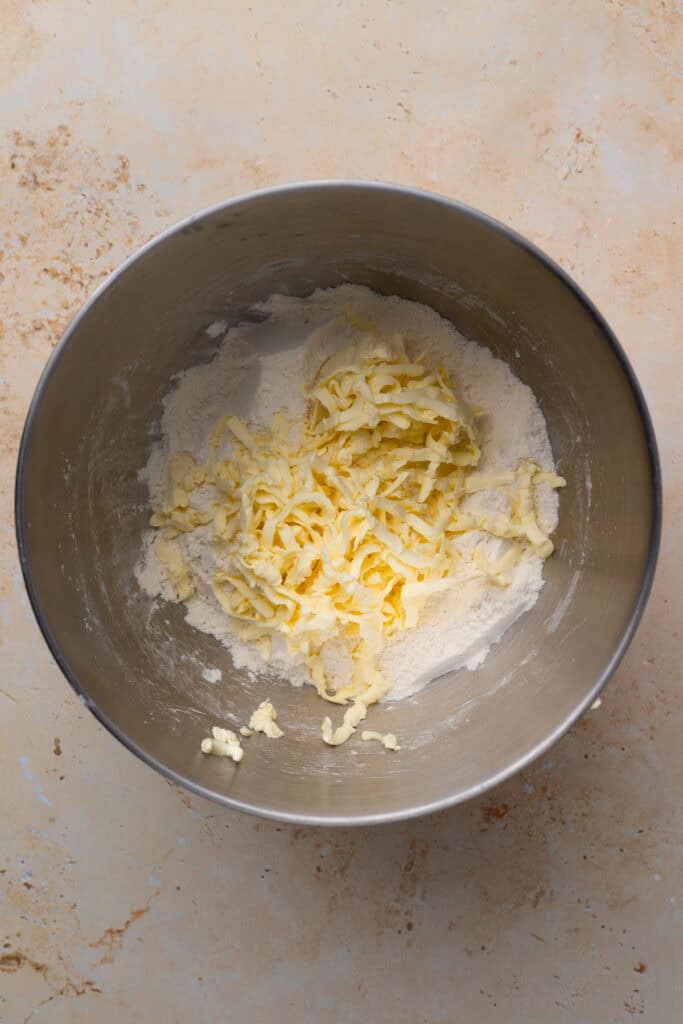 gluten free buttermilk biscuit dough ingredients with grated butter in a silver bowl