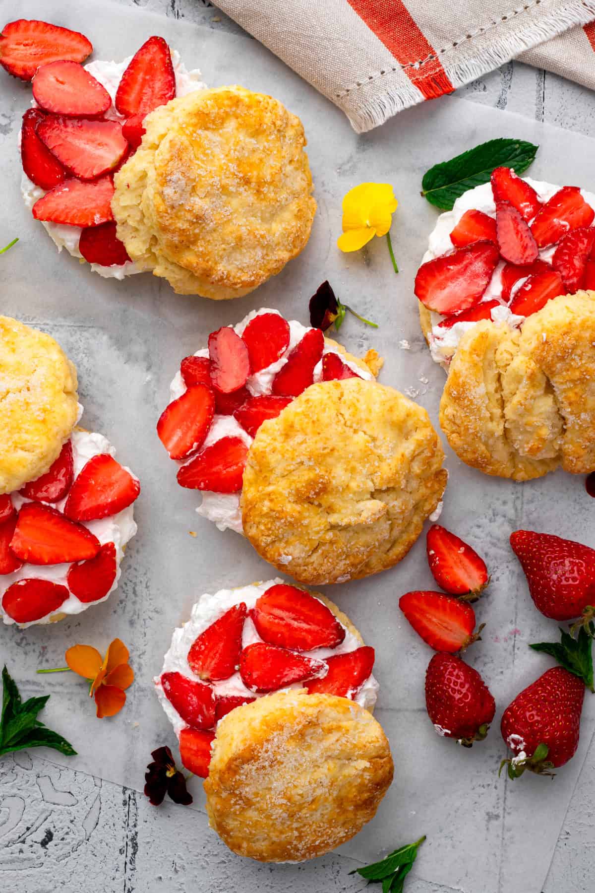 many gluten free strawberry shortcakes topped with whipped cream and sliced strawberries