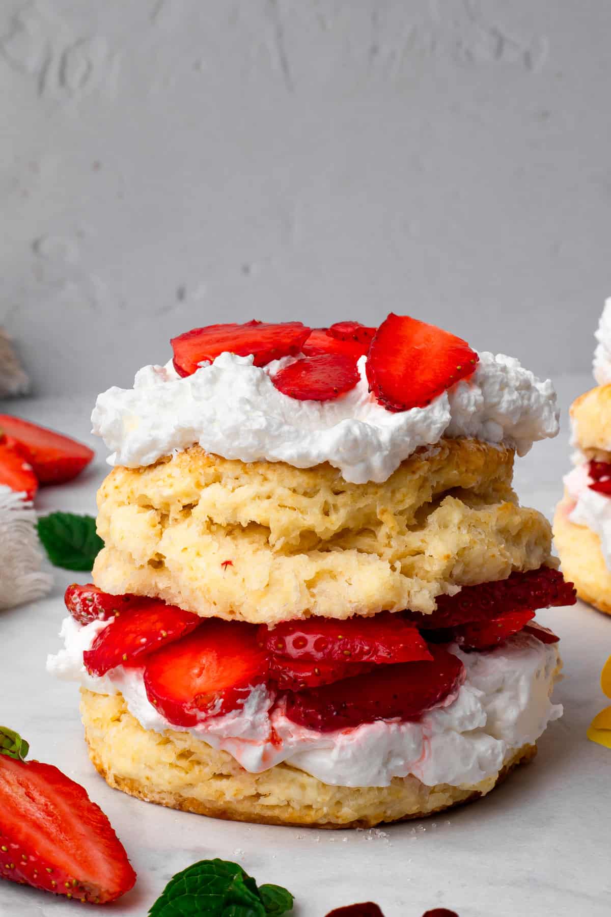 Stacked gluten free strawberry shortcakes with whipped cream and fresh sliced strawberries