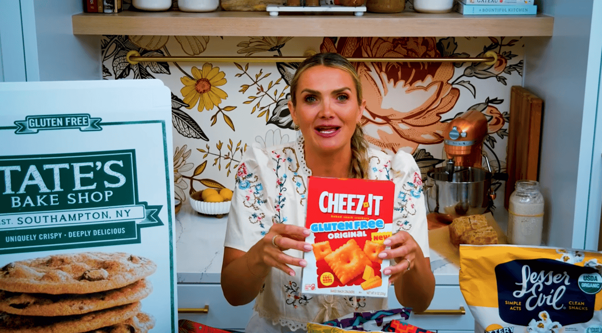 25+ gluten free snacks on a counter with a girl holding one of them